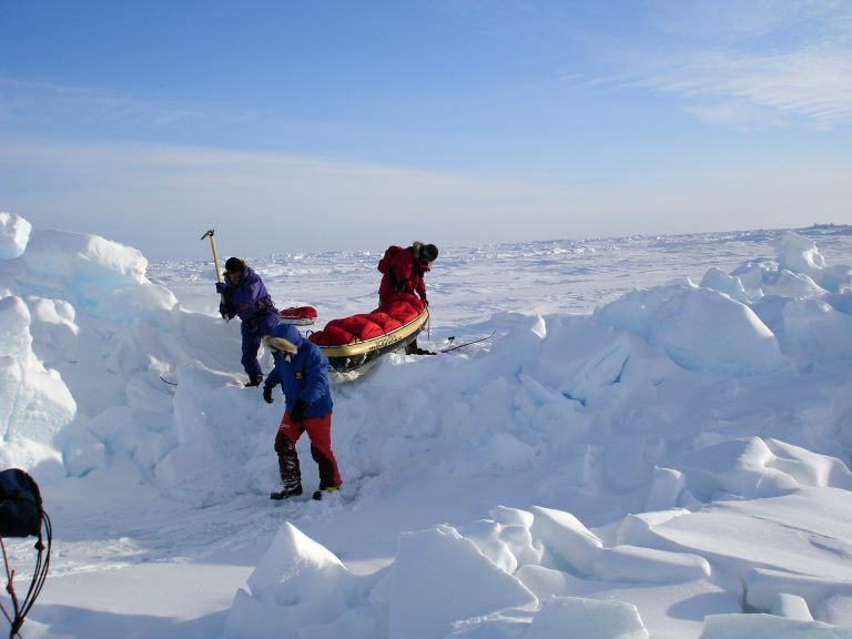 Professional skiers cross pressure ridge.